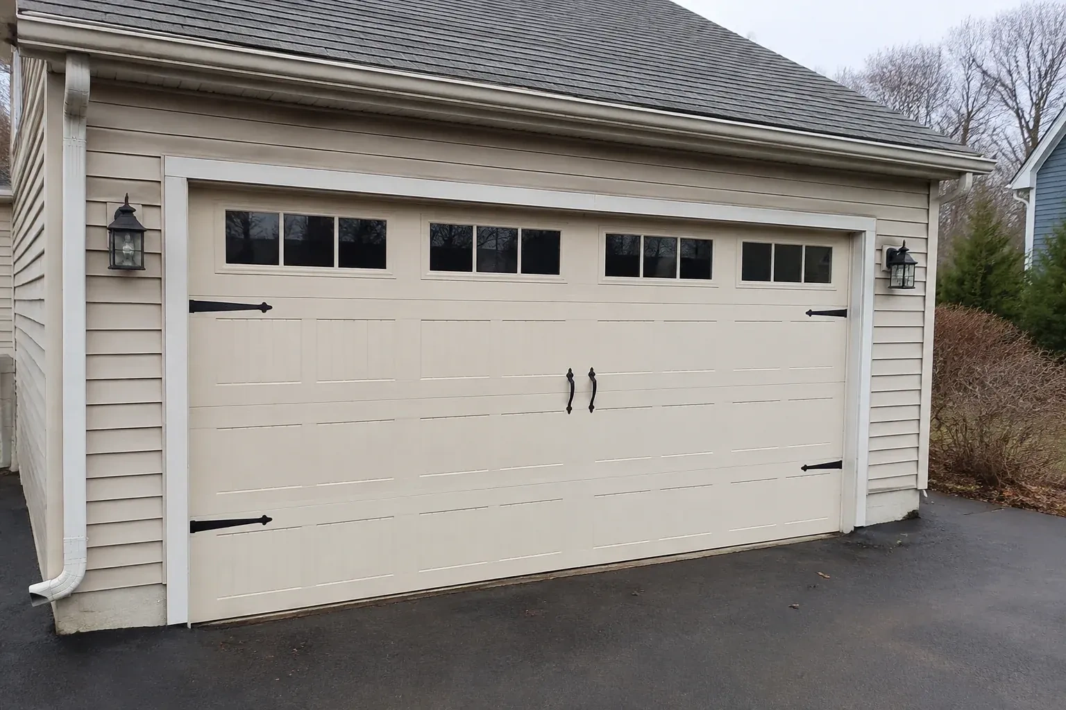 Cream carriage-house-style garage door with dark decorative hardware. — Carriage-House Garage Door Installation, Brampton